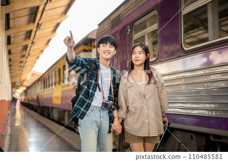 Asian couple travelers are commuting by train together, walking on a platform at a railway station. 110485581