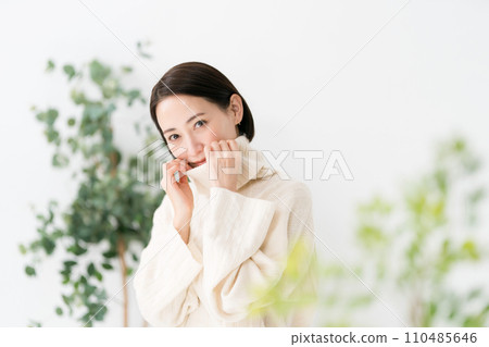 A woman in her 30s wearing a white knit 110485646