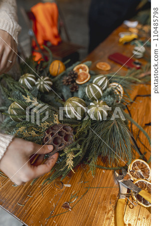 Engaging in a masterclass, a young lady creates Christmas decorations. Engaging in a masterclass, a young lady creates Christmas decorations. 110485798
