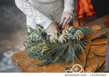 A young woman is actively involved in a workshop crafting Christmas ornaments. 110485804