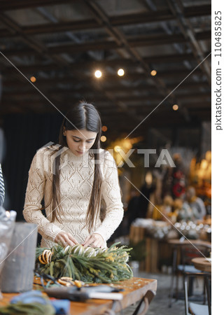 A young woman attends a masterclass to learn the art of crafting Christmas decorations. A young woman attends a masterclass to learn the art of crafting Christmas decorations. 110485825