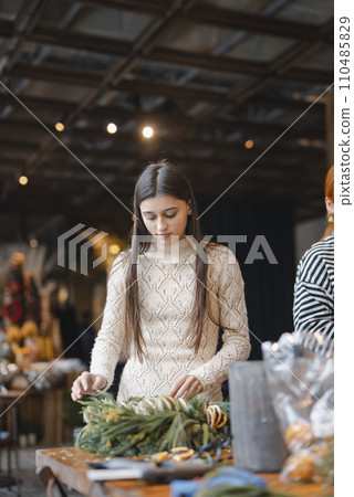 Actively involved in a workshop, a young lady creates handmade Christmas ornaments. 110485829