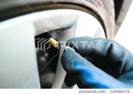 Car mechanic hand remove or close a tire valve cap of car wheel , Car maintenance service concept Car mechanic hand remove or close a tire valve cap of car wheel , Car maintenance service concept 110486372