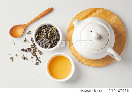 Cup of tea with dried tea leave, wood spoon and teapot on beige background, top view Cup of tea with dried tea leave, wood spoon and teapot on beige background, top view 110487086