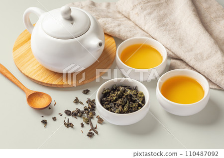 Tea cups, teapot and dried tea leave with spoon and napkin, tea set on table 110487092