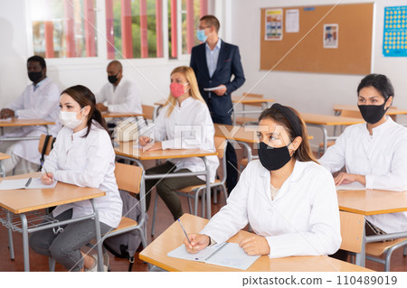Adult medical students in protective masks attending refresher course Adult medical students in protective masks attending refresher course 110489019