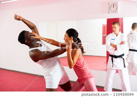 Woman painful eye blow to african american man in self defense training Woman painful eye blow to african american man in self defense training 110489094