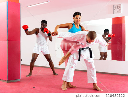Woman exercising with trainer and man boxing in gym 110489122