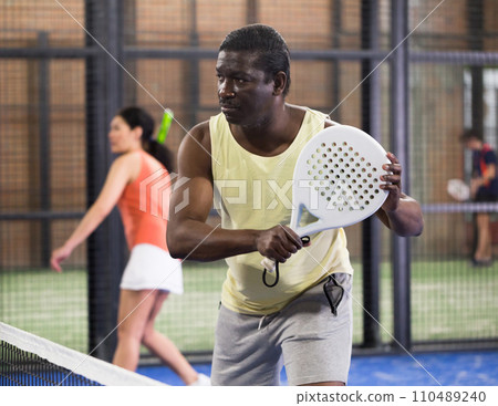 African American hitting backhand during paddle match in close court African American hitting backhand during paddle match in close court 110489240