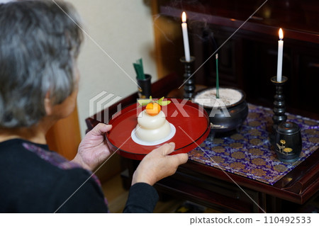 一位老婦人向佛壇供奉年糕 110492533