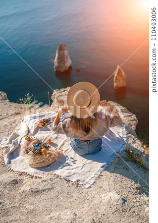 woman sea travel. photo of a beautiful woman with long blond hair in a pink shirt and denim shorts and a hat having a picnic on a hill overlooking the sea woman sea travel. photo of a beautiful woman with long blond hair in a pink shirt and denim shorts and a hat having a picnic on a hill overlooking the sea 110493006
