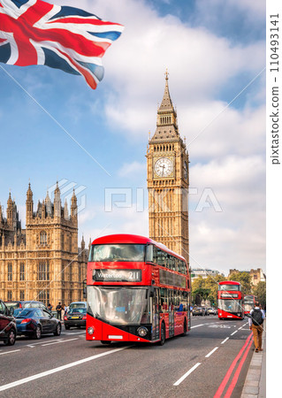 Big Ben with red buses on the bridge against flag of England in London, England, UK Big Ben with red buses on the bridge against flag of England in London, England, UK 110493141
