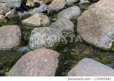 water flowing in a small narrow stream in summer 110493982