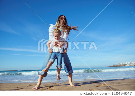 Caucasian happy little child girl and her mom having fun together on the beach Caucasian happy little child girl and her mom having fun together on the beach 110494047