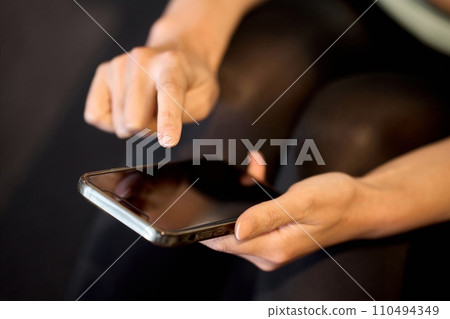 一位女士使用智慧型手機應用程式管理她的健身房 110494349
