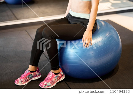 Woman sitting on balance ball at gym 110494353