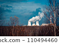 Nuclear power plant cooling towers concept photo. Big chimneys. Forest with partly cloudy sky in Polish province. 110494460