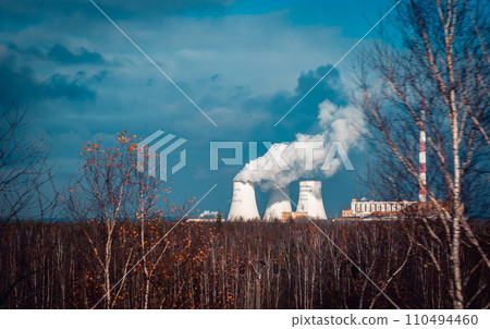 Nuclear power plant cooling towers concept photo. Big chimneys. Forest with partly cloudy sky in Polish province. 110494460