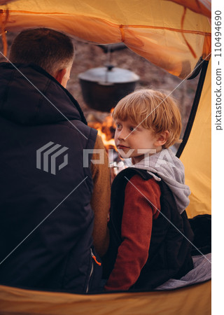 Man and boy tourists autumn time leisure, vacation hiking or traveling touristic activity. Family camping, father and little son relax in forest camp. Man and boy tourists autumn time leisure, vacation hiking or traveling touristic activity. Family camping, father and little son relax in forest camp. 110494690