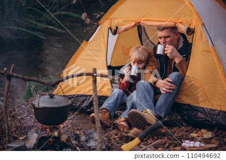 Man and boy tourists autumn time leisure, vacation hiking or traveling touristic activity. Family camping, father and little son relax in forest camp. 110494692