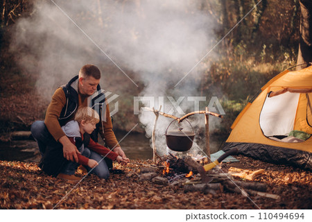 Man and boy tourists autumn time leisure, vacation hiking or traveling touristic activity. Family camping, father and little son relax in forest camp. Man and boy tourists autumn time leisure, vacation hiking or traveling touristic activity. Family camping, father and little son relax in forest camp. 110494694