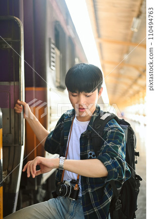 It's time to get on the train. Traveler male with backpack checking time on wrist watch and getting on the train It's time to get on the train. Traveler male with backpack checking time on wrist watch and getting on the train 110494763