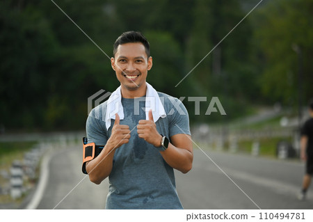 Smiling muscular man showing thumbs up for symbol good health. Sport and healthy life concept 110494781