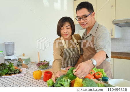 Attractive senior couple in casual outfits cooking together in kitchen. Healthy lifestyle concept 110494826
