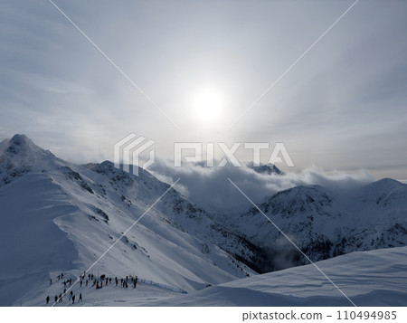 Snowy fog or blizzard on Tatras mountain peak in winter. Hiking trail with tourists, popular place in Poland, Kasprowy Wierch. 110494985