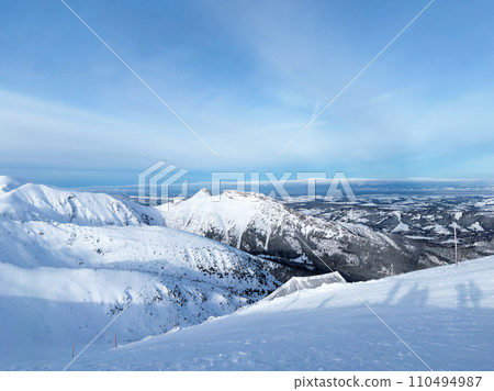 Top of mountain, snowy peaks of Tatras mountain, beautiful landscape, winter tourism. Kasprowy Wierch in day with good weather, blue sky Top of mountain, snowy peaks of Tatras mountain, beautiful landscape, winter tourism. Kasprowy Wierch in day with good weather, blue sky 110494987