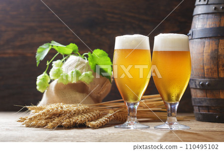 Glasses of beer, wheat ears, hops and beer barrel on a wooden background Glasses of beer, wheat ears, hops and beer barrel on a wooden background 110495102