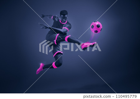 African young man, soccer player in mid-kick with selective purple coloring, illustrating movement and focus. 110495779