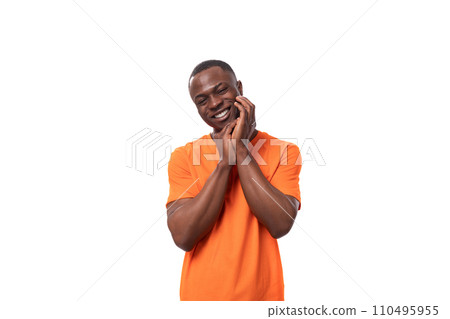 young well-groomed slender African guy dressed in an orange t-shirt with a mockup on a white young well-groomed slender African guy dressed in an orange t-shirt with a mockup on a white 110495955