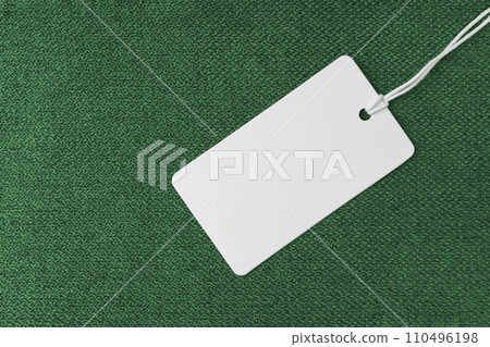 Textile background, green coarse fabric texture with white empty clothing tag Textile background, green coarse fabric texture with white empty clothing tag 110496198