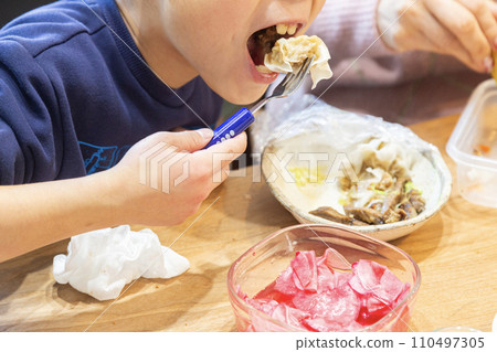 7 year old boy eating with his family 110497305