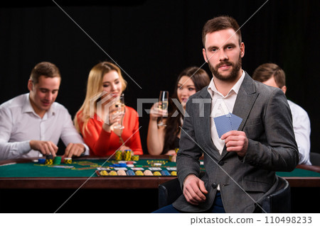 Poker players in casino with cards and chips on black background Poker players in casino with cards and chips on black background 110498233