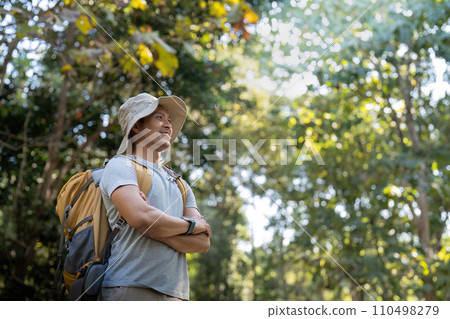 Young man asian trekking among trees with backpack, young man enjoy alone in forest. Camping, hiking, travelling, search for adventure concept Young man asian trekking among trees with backpack, young man enjoy alone in forest. Camping, hiking, travelling, search for adventure concept 110498279