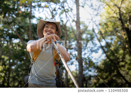 Young man asian trekking among trees with backpack, young man enjoy alone in forest. Camping, hiking, travelling, search for adventure concept Young man asian trekking among trees with backpack, young man enjoy alone in forest. Camping, hiking, travelling, search for adventure concept 110498308