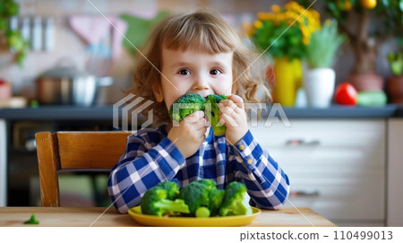 happy child eats broccoli in modern kitchen. portrait happy child eats broccoli in modern kitchen. portrait 110499013
