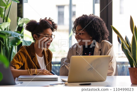 two people sitting at a table in an office and talking 110499023