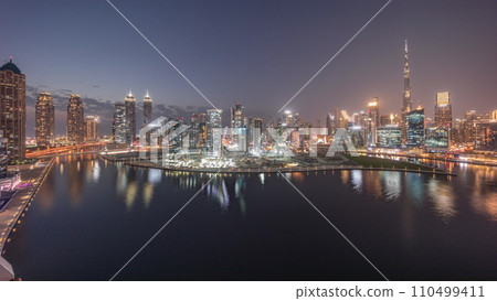 Aerial panorama of Dubai Business Bay and Downtown with the various skyscrapers and towers day to night timelapse 110499411