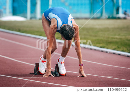 senior woman runner running start 200 metres race in masters athletics 110499622