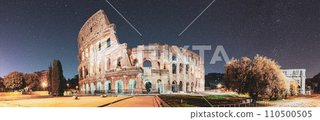Rome, Italy. Colosseum Also Known As Flavian Amphitheatre In Evening Or Night Time. Bold Bright Blue Night Starry Sky With Glowing Stars Above Colosseum. Panoramic View. Travel To Italy 110500505