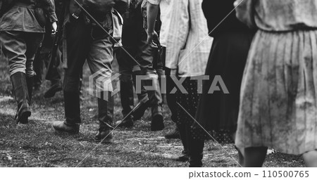Group Of Re-enactors Dressed As Soviet Russian Soldiers Escort Civilians. Soviet Russian Soldiers Uniform. Evacuation Of Civilians. Black And White 110500765