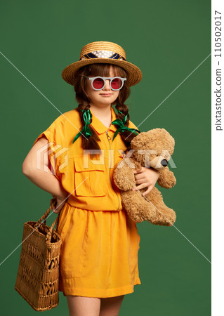 Portrait of beautiful little girl with down syndrome wearing hat, sunglasses and yellow suit against green studio background Portrait of beautiful little girl with down syndrome wearing hat, sunglasses and yellow suit against green studio background 110502017