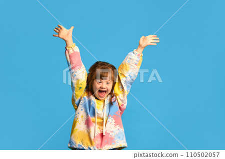 Careless and caring childhood. Happy smiling girl, child with down syndrome against blue studio background Careless and caring childhood. Happy smiling girl, child with down syndrome against blue studio background 110502057