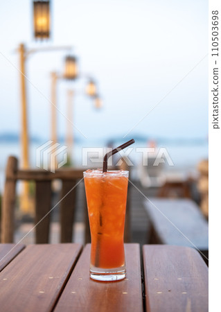 A glass of Mai Tai, a cocktail made of rum on the table with view of the beach A glass of Mai Tai, a cocktail made of rum on the table with view of the beach 110503698