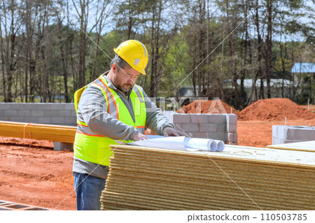 Build engineer checks construction of new home using construction plan during construction Build engineer checks construction of new home using construction plan during construction 110503785