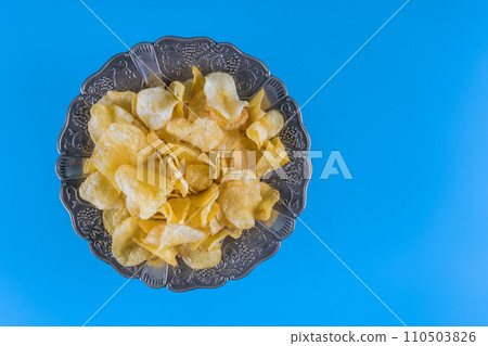 This is top view plate of potato chips against blue background This is top view plate of potato chips against blue background 110503826