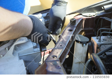 Repairman assembling vehicle headlight during car maintenance Repairman assembling vehicle headlight during car maintenance 110503830